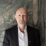 Bilde av forfatter Lars Saabye Christensen i hvit skjorte og sort dressjakke.