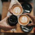 tre hender som skåler med kaffe og cola, sett ovenfra