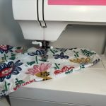 nærbilde av symaskin og et blomstret stoff